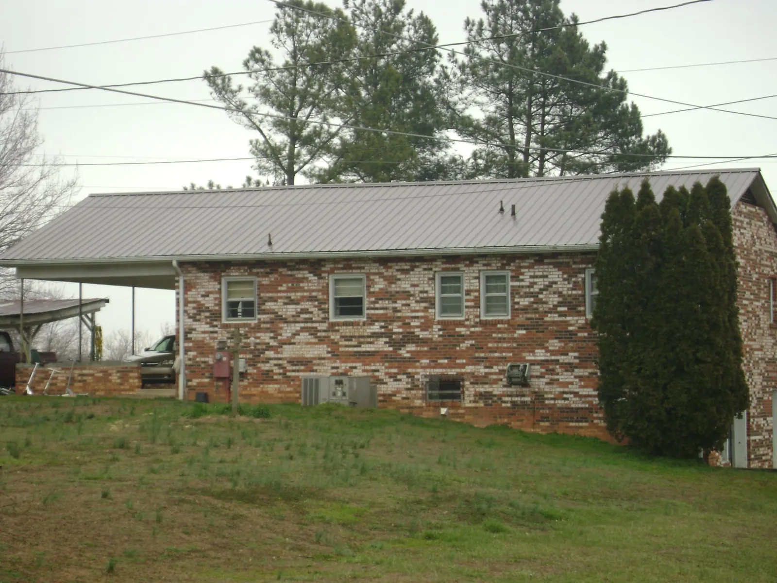 Gray metal roof on a brick split level home with a carport in Centerville