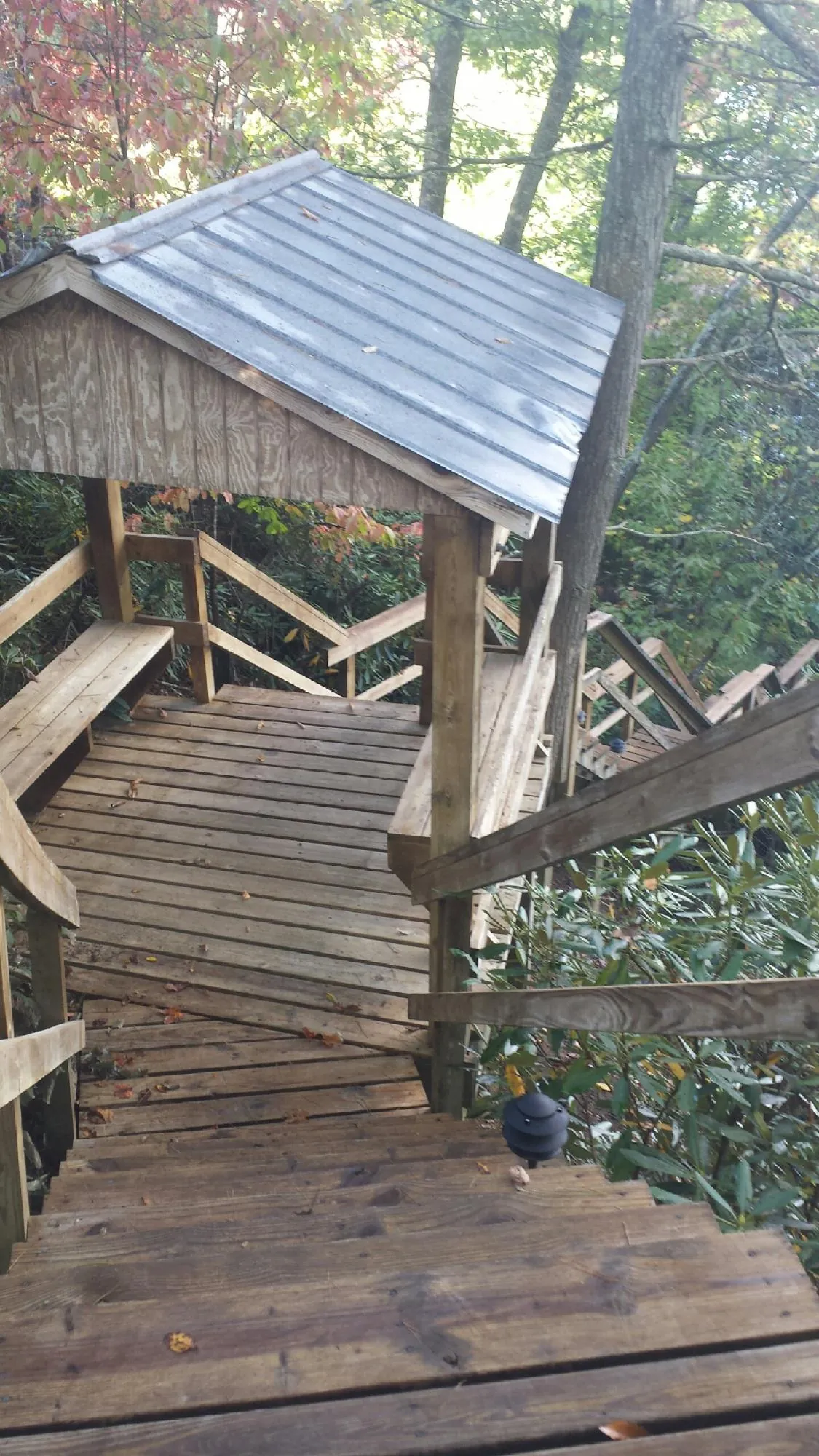 Metal roofed shelter over wooden steps on a wooded walkway — Skylight Repair & Installation work by our crew in Centerville